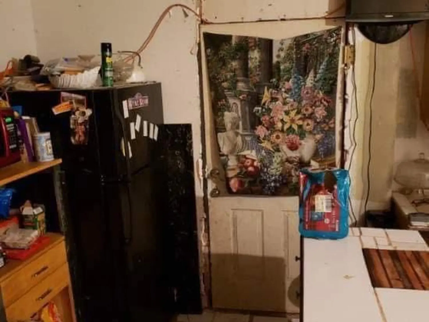 Kitchen area before full remodel with heavy clutter and damaged finishes
