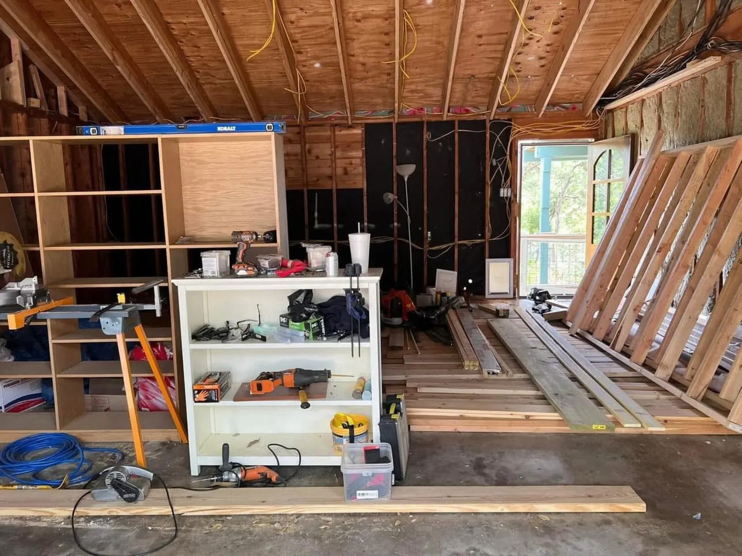 Garage remodel before with exposed framing and material stack